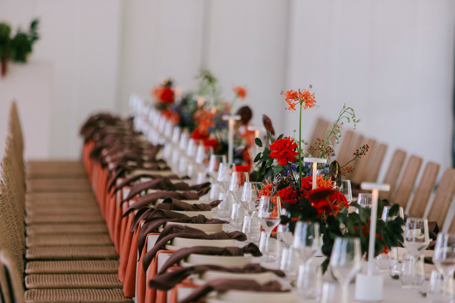 Elegant table setting with vibrant red and orange floral centerpieces in Melbourne.