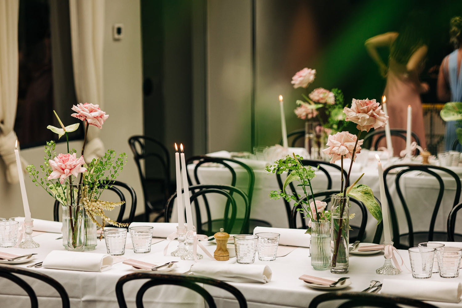 Elegant wedding table setting with pink floral centerpieces and candlelight.