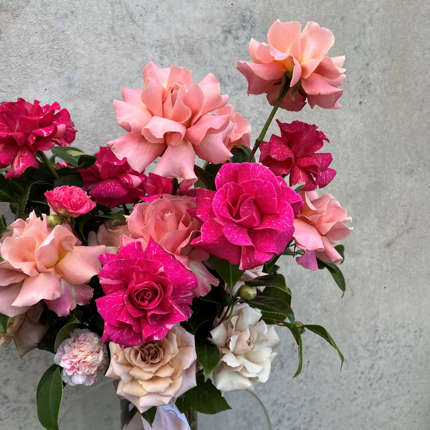 Vibrant bouquet of pink and red fresh roses against a neutral background.