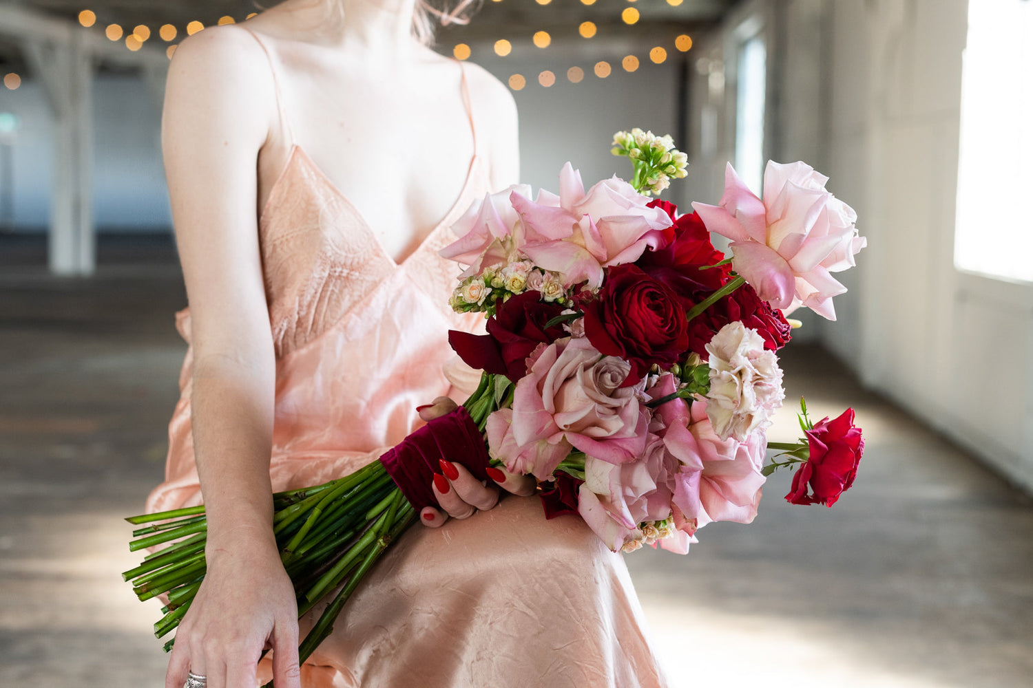 Woman in pink dress holding a bouquet of red and pink roses, perfect Valentine's Day gift.