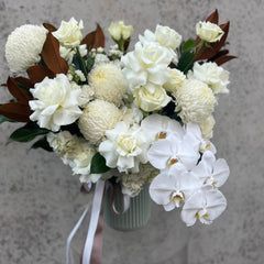 Sophisticated white floral arrangement featuring roses, orchids, and chrysanthemums in a ribbed vase with ribbon accents. Ideal for Valentine's Day.