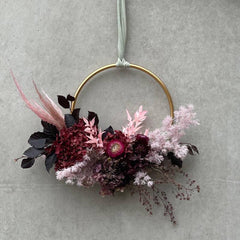 Pink coloured wreath with artificial flowers and autumn foliage