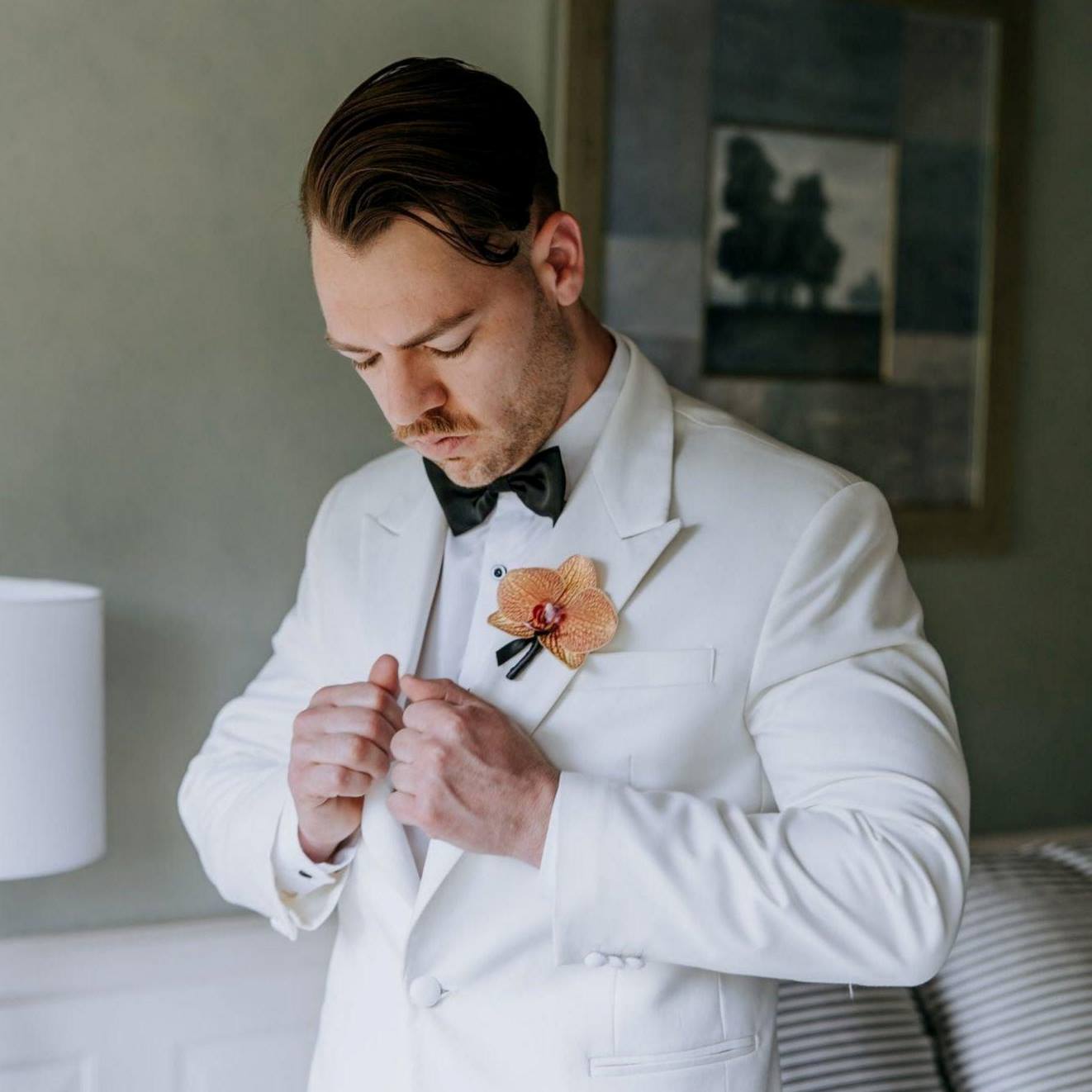 orchid groom button hole on a white suit