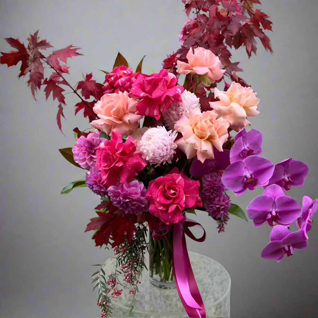 Florist Choice Valentine's Day bouquet featuring pink roses, purple orchids, and red foliage in a glass vase. Perfect for Melbourne delivery.