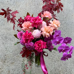 Florist Choice Valentine's Day bouquet featuring pink roses, purple orchids, and red foliage in a glass vase. Perfect for Melbourne delivery.